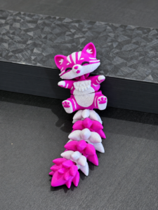 Figurine articulée rose et blanche imprimée en 3D.